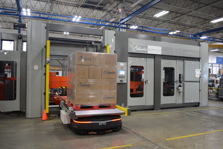 Image of a FL6200SW floor level palletizer with a self-driving OTTO vehicle moving a pallet load.
